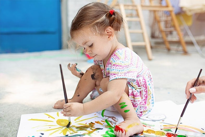 Young girl sitting painting a picture