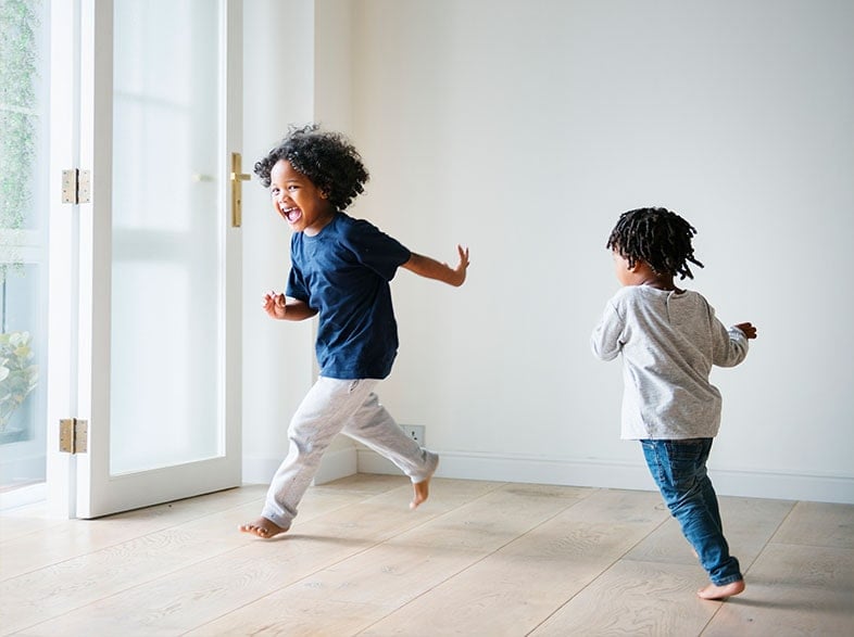 Two young children skipping indoors