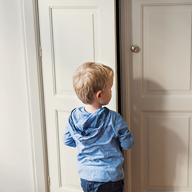 Young child standing at a slightly open door