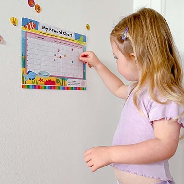 Girl sticking stickers on a reward chart