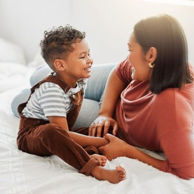 Mom and son sitting on a bed talking