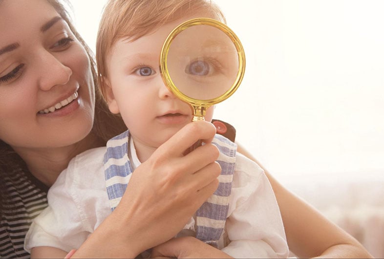 Mom holding a magnifying glass for a baby to look through