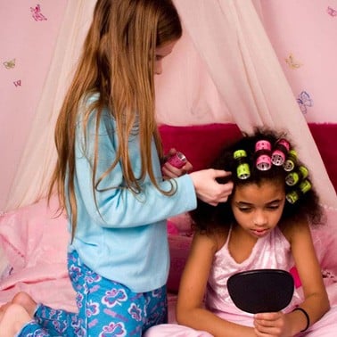 Girl putting curlers in her friend's hair