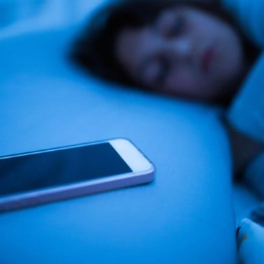 Sleeping girl with a cell phone on a night stand