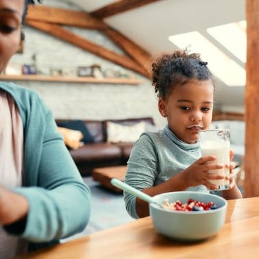 Young girl drinking milk at a breakfast table