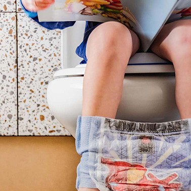 Boy on a toilet reading a book