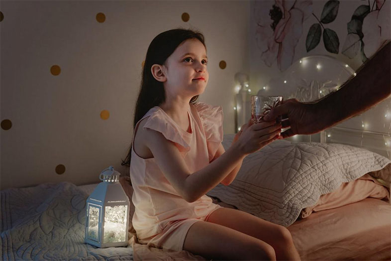Girls sitting on the side of her bed holding mom's hand