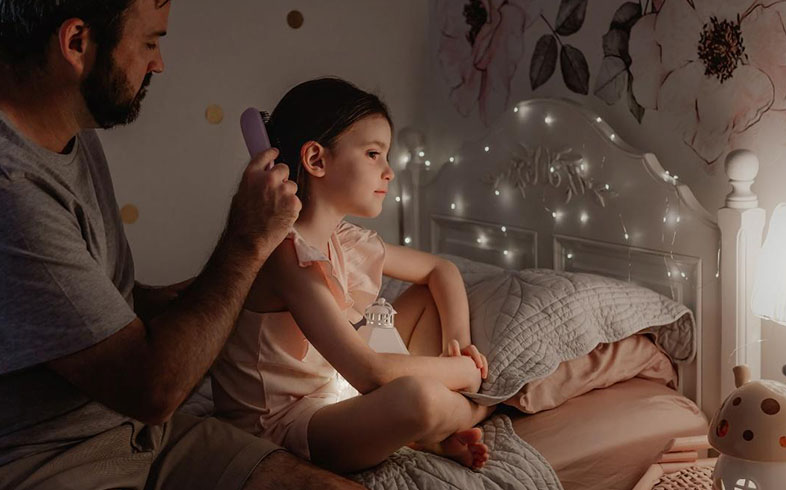 Dad brushing his daughter's hair before bed