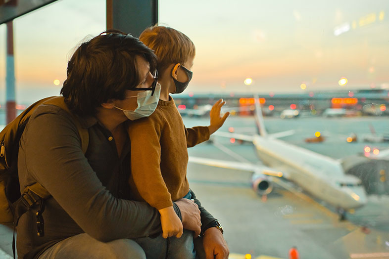 Dad and son at airport waving at a plane