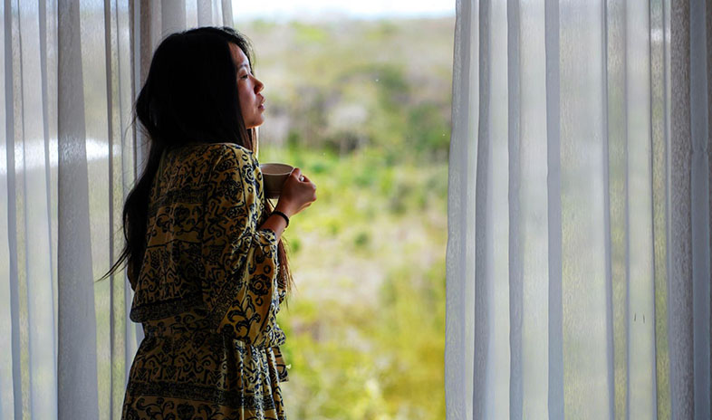 Woman looking out of the window while holding a mug