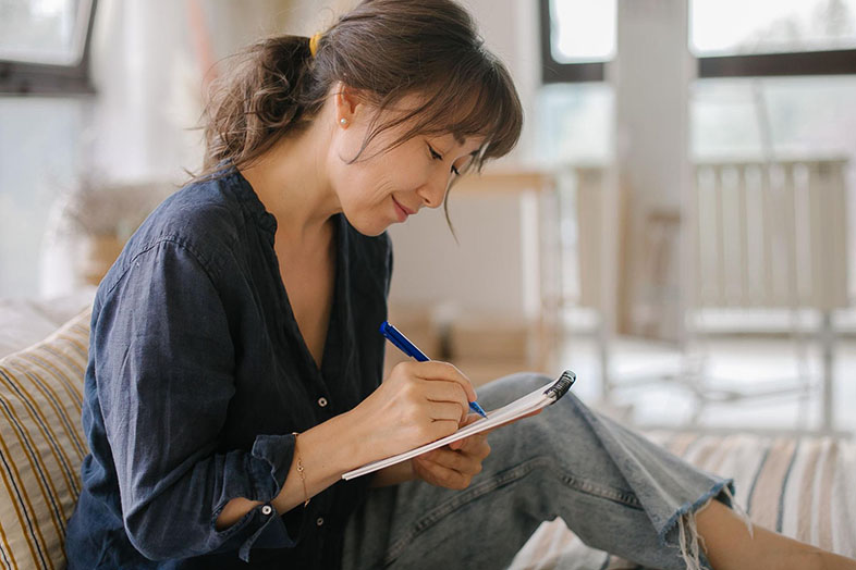 Smiling woman sitting on a couch journalling