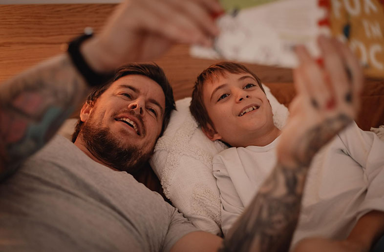 Dad and son reading a book in bed