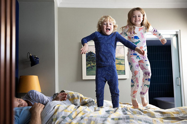 Siblings jumping on a bed