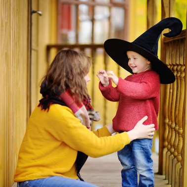 Mom kneeling next to her child in character hat