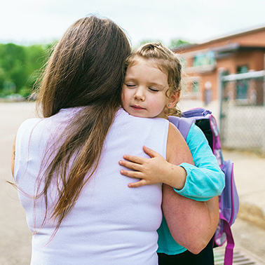 Mom hugging her daughter at school