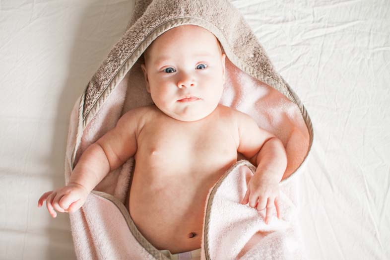 baby wrapped up in a pink and brown towel after their first bath