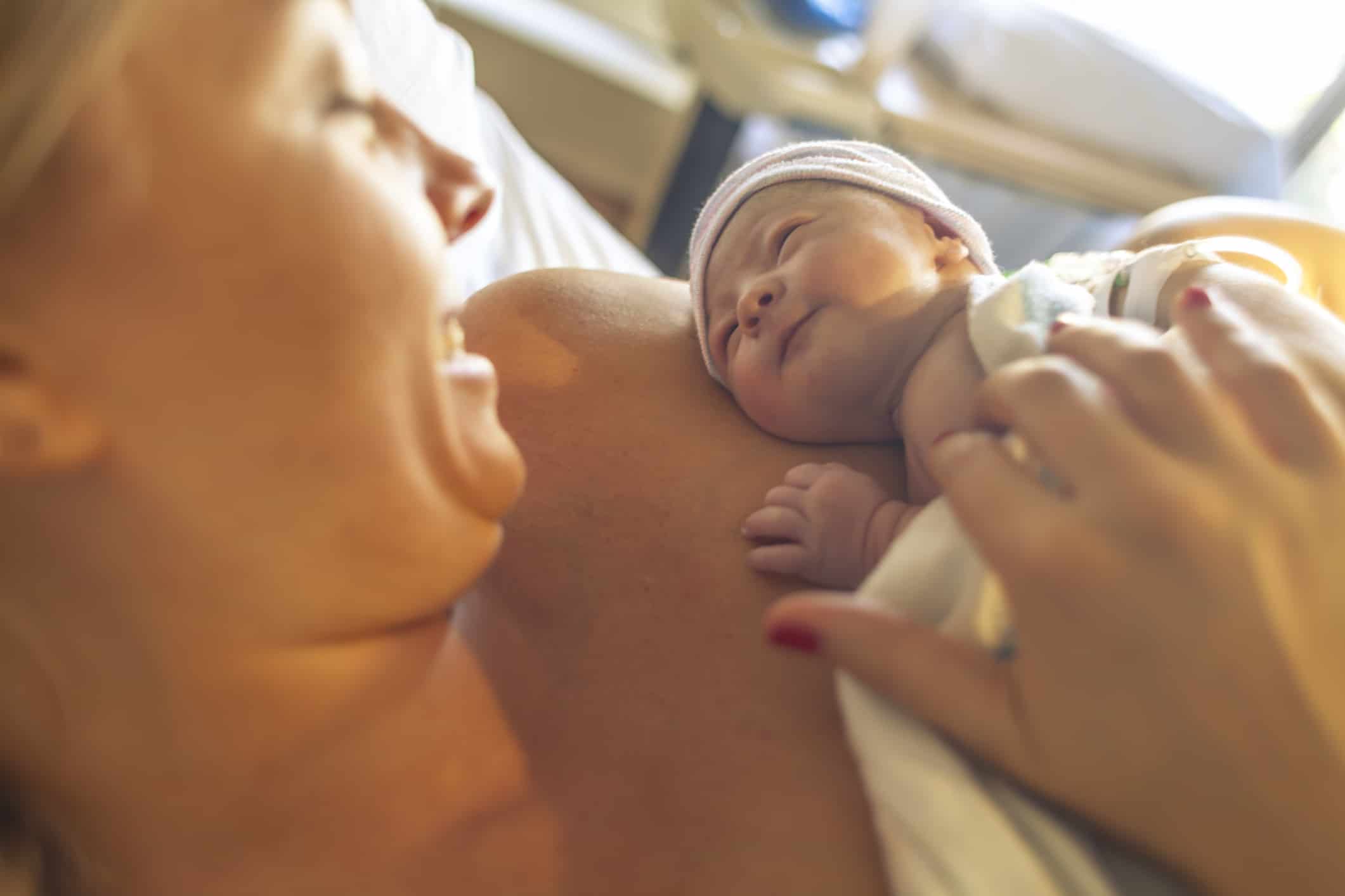 A mother smiling at her newborn baby as they enjoy some skin-to-skin time together