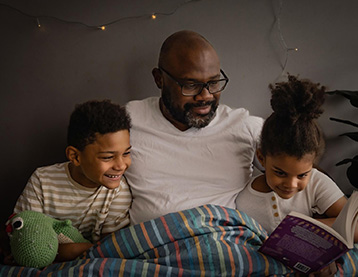 Dad and kids reading a book in bed