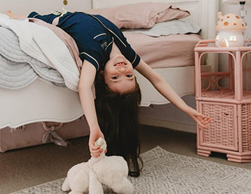 Young girl hanging carefree off her bed